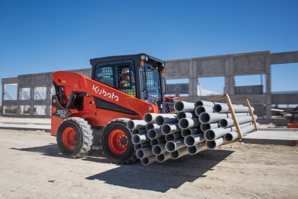 Kubota SSV skid steer carrying a load of pipe on a jobsite