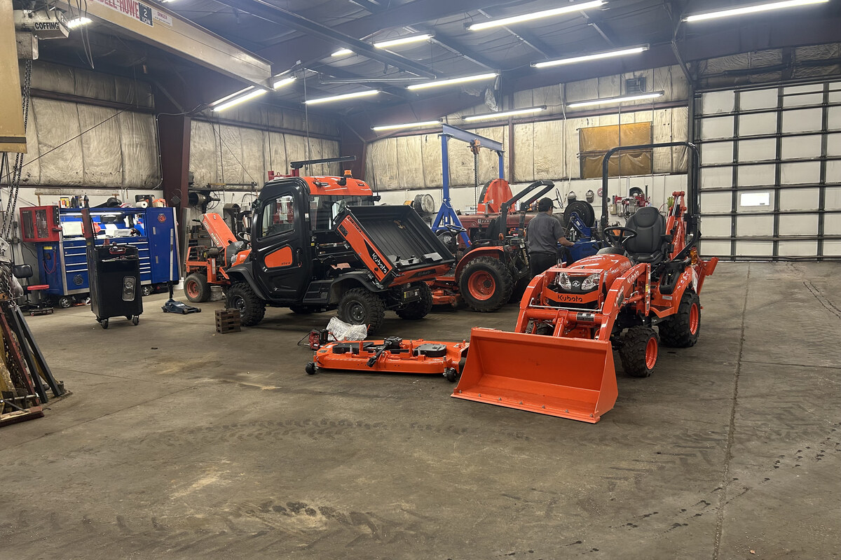 Unkefer Sales service bay with Kubota tractors and a technician at work